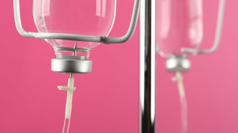 An IV bottle with a bright pink background